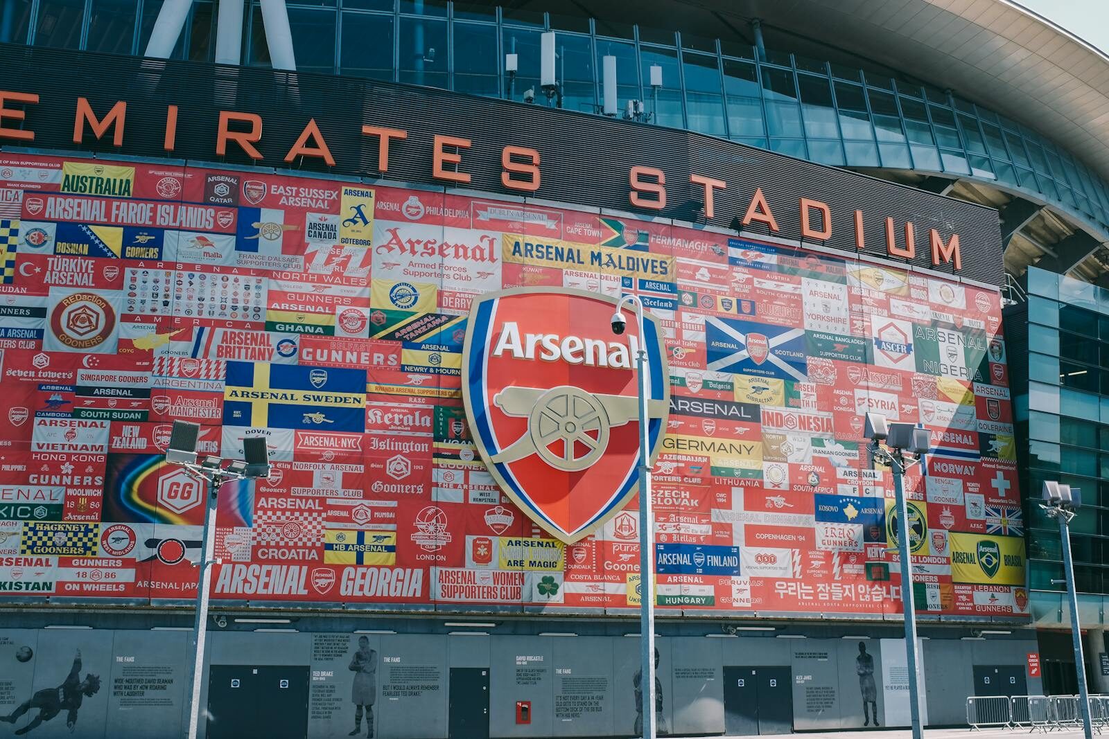 Vibrant wall art at Emirates Stadium featuring Arsenal flags and crest in London, UK.