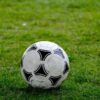 Close-up of a classic soccer ball resting on a lush green field.