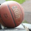 A detailed image showcasing a basketball resting on a park bench, highlighting texture and outdoor setting.