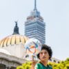 A young man spins a football in front of Torre Latinoamericana and Palacio de Bellas Artes.