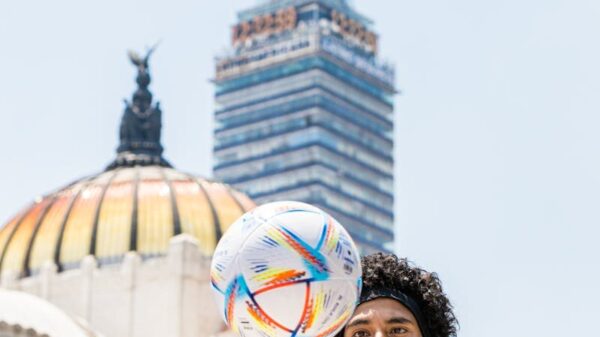 A young man spins a football in front of Torre Latinoamericana and Palacio de Bellas Artes.