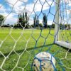 Vibrant shot of a soccer ball trapped in the goal net on a sunny day.