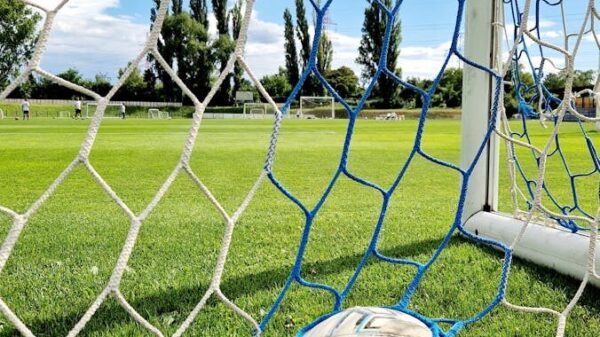 Vibrant shot of a soccer ball trapped in the goal net on a sunny day.