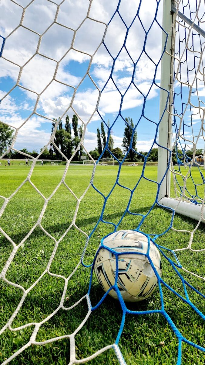 Vibrant shot of a soccer ball trapped in the goal net on a sunny day.