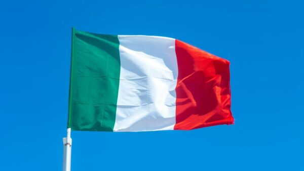 The Italian flag waves vibrantly against a clear blue sky, symbolizing national pride.