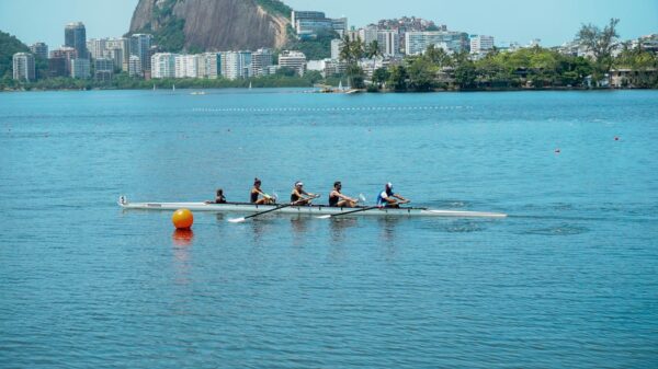 A team of rowers paddling on a serene lake in Rio de Janeiro with iconic landscape in the background.