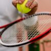 Close-up view of a person holding a tennis ball on a racket on the court.