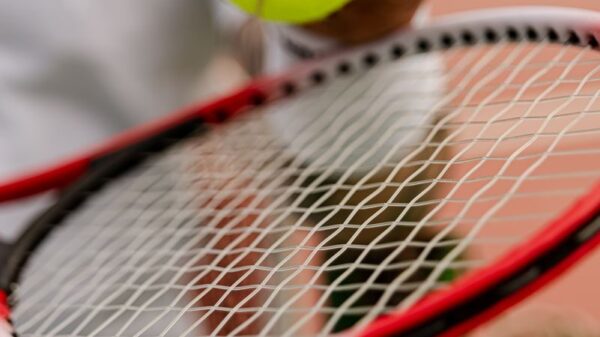 Close-up view of a person holding a tennis ball on a racket on the court.
