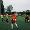 Young kids playing soccer on a green field during the day. Engaged in a fun sporting activity.