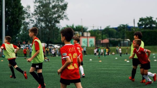 Young kids playing soccer on a green field during the day. Engaged in a fun sporting activity.