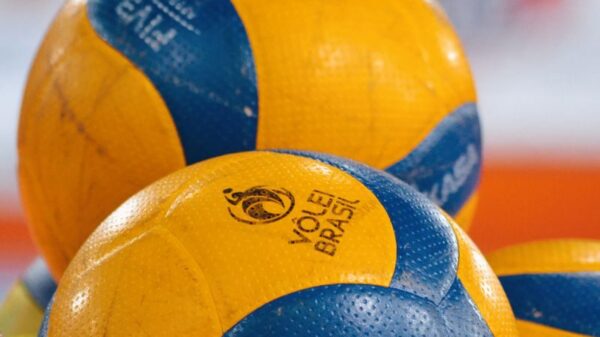 Bright yellow and blue volleyballs stacked in an indoor sports environment.
