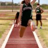 Athlete performing long jump outdoors on track field during daytime event