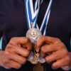 Close-up of hands holding a silver medal showcasing achievement and recognition.
