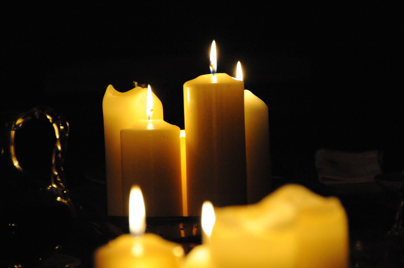 Cozy ambience with close-up of flickering candles on a dark background.
