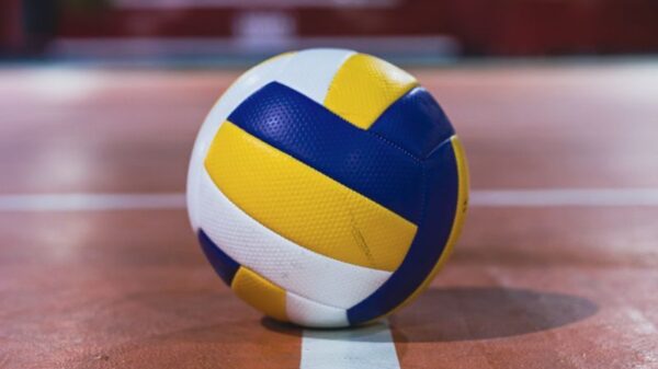 Close-up of a volleyball resting on the line of an indoor court, focus on the ball.