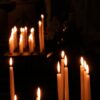 A tranquil scene of lit candles in a dark chapel, evoking peace and reflection.