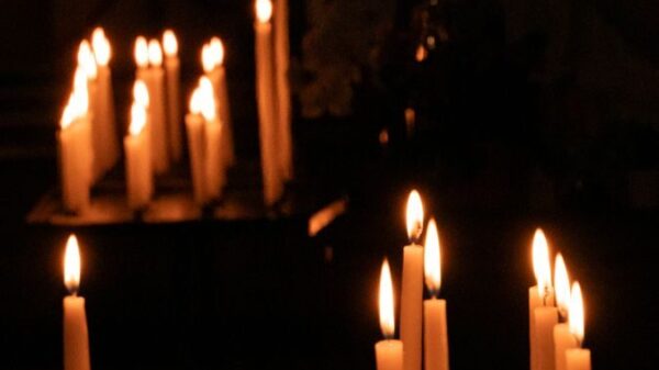 A tranquil scene of lit candles in a dark chapel, evoking peace and reflection.