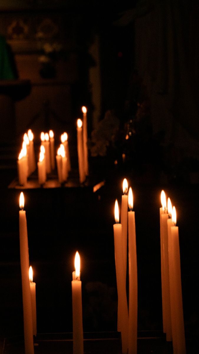 A tranquil scene of lit candles in a dark chapel, evoking peace and reflection.