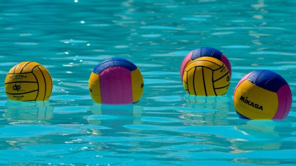 Vibrant water polo balls drifting on clear turquoise water under the sun.