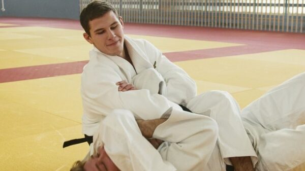 Two male adults engaged in judo practice on a dojo mat, showcasing martial arts technique.